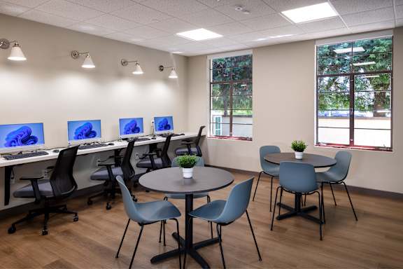 A room with a table, chairs, and computer screens.