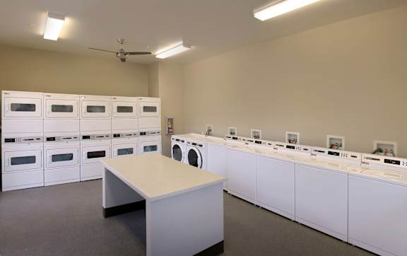 A room with a table and a wall of washing machines.