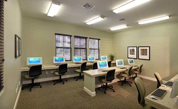A room with multiple computers and chairs.
