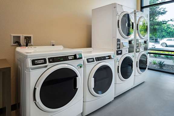 A row of white front load washing machines in a store.