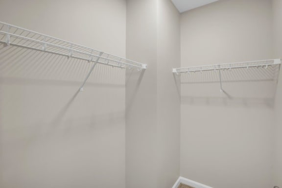 a walk in closet with white walls and a mirrored closet door