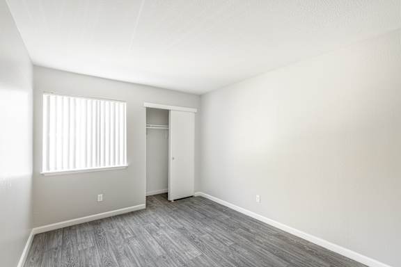 an empty bedroom with hardwood floors and a large window