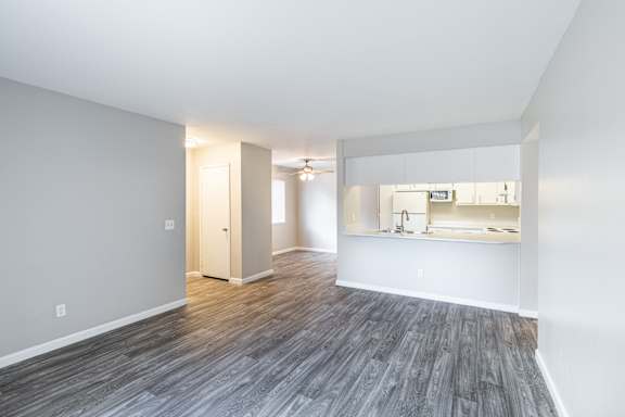 an empty living room with a kitchen in the background