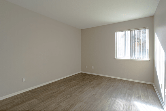 a bedroom with hardwood floors and a window