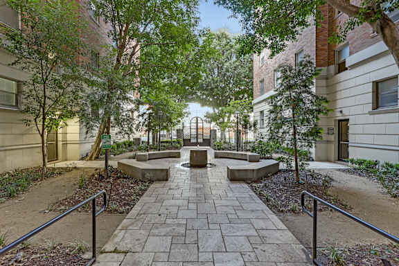 A courtyard with a brick pathway and trees.at Park Wilshire, Los Angeles, 90057