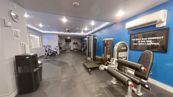 a gym with weights and cardio equipment and a sign on the wall