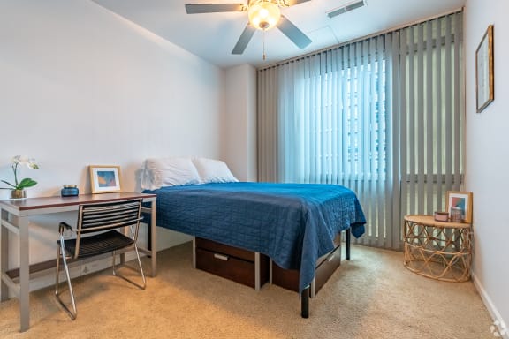a bedroom with a bed and a desk and a ceiling fan