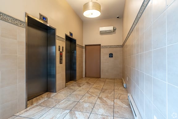 two elevators in a hallway with tiled floors and walls
