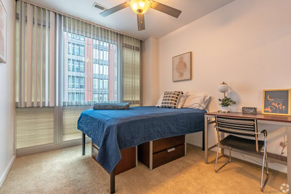 a bedroom with a bed and a desk and a ceiling fan