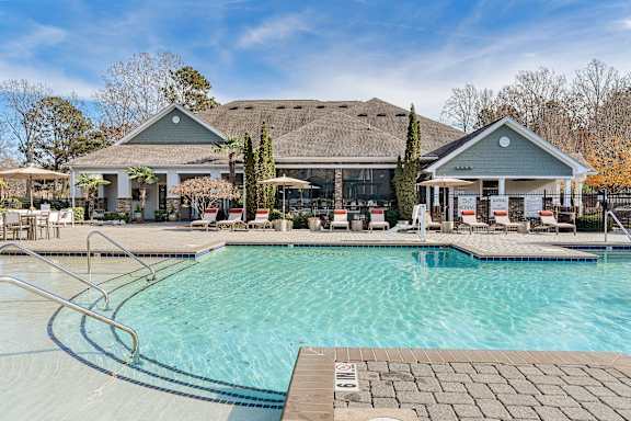 A large swimming pool in front of a house with a patio and chairs. at Echo at Lake Norman, Mooresville, NC