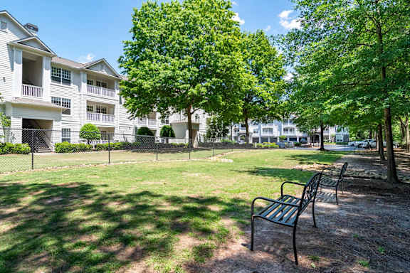 A park with a bench and trees in front of apartment buildings.