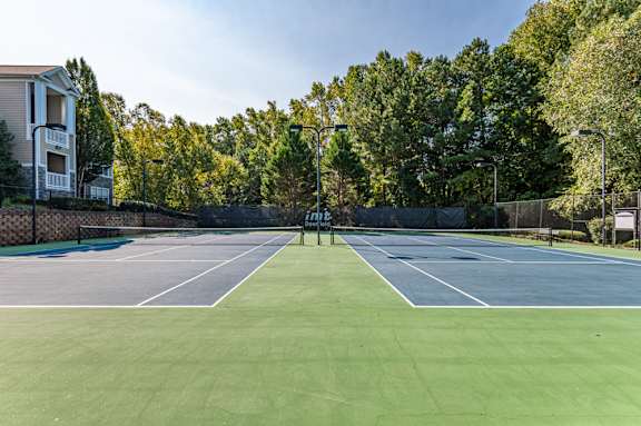 A tennis court surrounded by a fence and trees.
