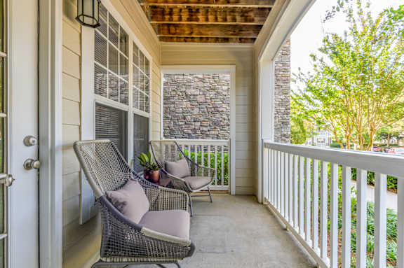A balcony with two chairs and a table.