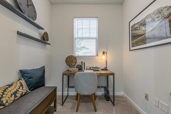 A room with a desk, chair, and a couch with a blue cushion.