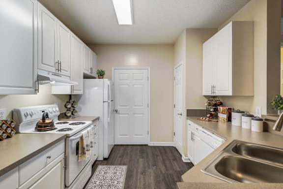 A kitchen with white cabinets and a white door.