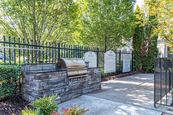 A gated entrance with a stone wall and a black fence.