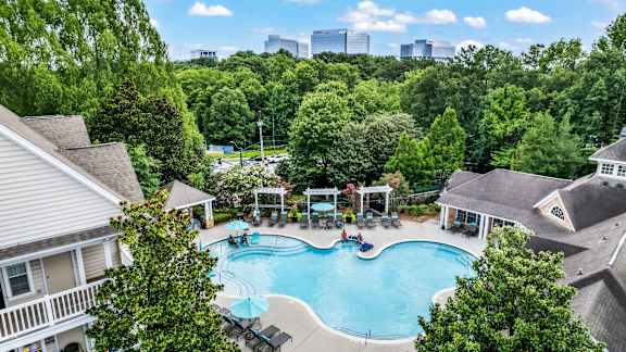 A swimming pool surrounded by trees and houses.