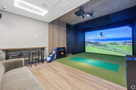A room with a large screen and a green mat on the floor.