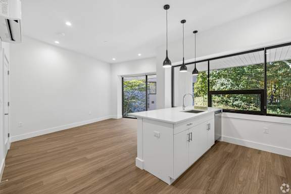 A kitchen with white cabinets and a wooden floor.