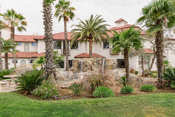 A house with a red tile roof and a palm tree in front.