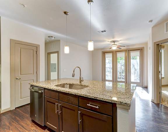 A kitchen with a granite countertop and wooden cabinets.