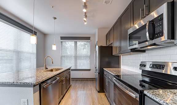 A modern kitchen with dark wood cabinets and stainless steel appliances.