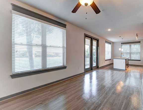 A room with a ceiling fan and sliding glass doors.