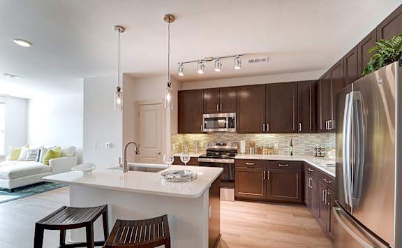 A modern kitchen with a white countertop and dark brown cabinets.