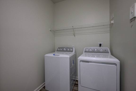 Two white front loading washing machines in a laundry room.