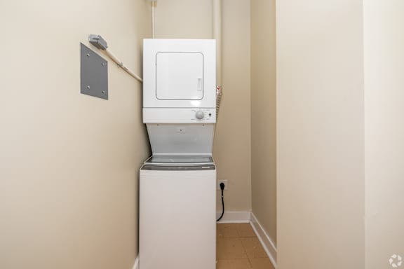 A white tankless water heater in a corner of a room.