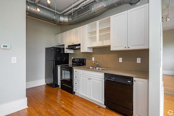A kitchen with black appliances and white cabinets.