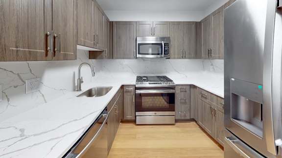 A modern kitchen with a marble countertop and stainless steel appliances.