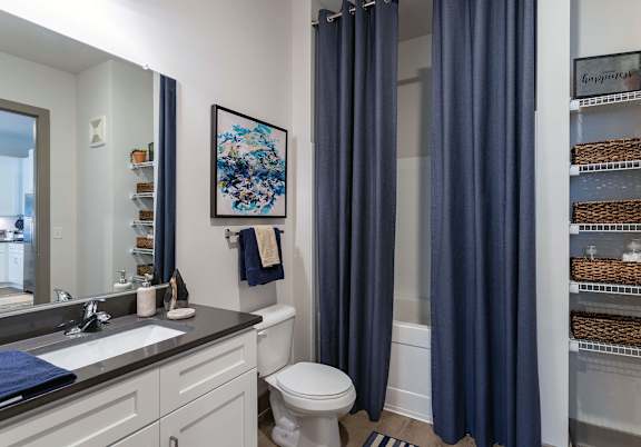 A bathroom with a toilet, sink, and blue curtains.