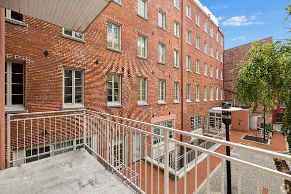 A red brick building with a balcony in front.