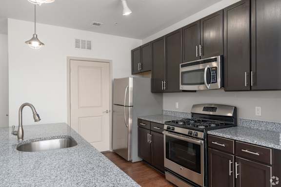 A kitchen with a granite countertop and stainless steel appliances.