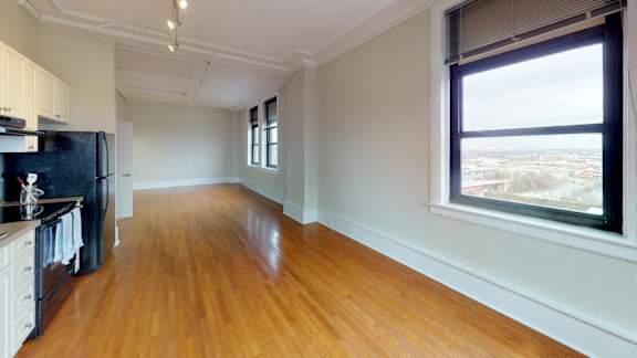 A kitchen with wooden floors and a large window overlooking a cityscape.