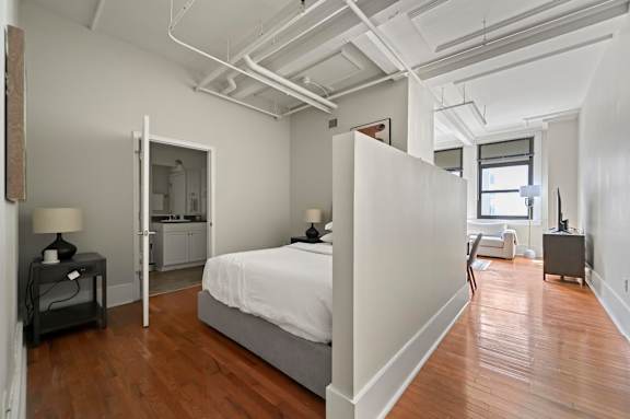 A bedroom with a bed, nightstand, and chair.