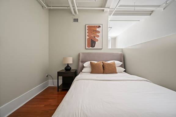 A bedroom with a bed, nightstand, and lamp.
