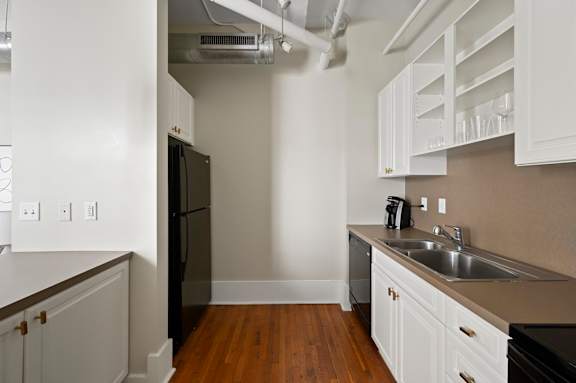 A kitchen with white cabinets and a black refrigerator.