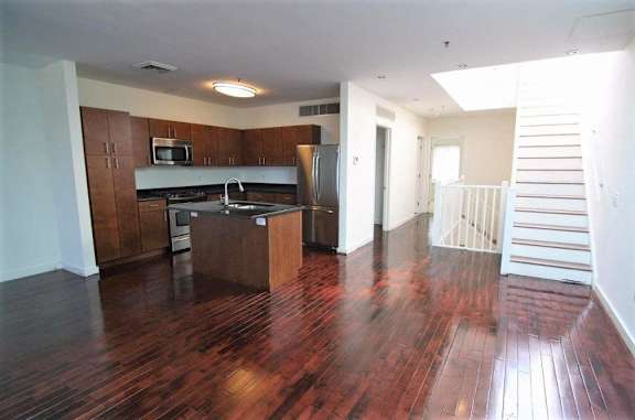 A kitchen with wooden floors and a white staircase.