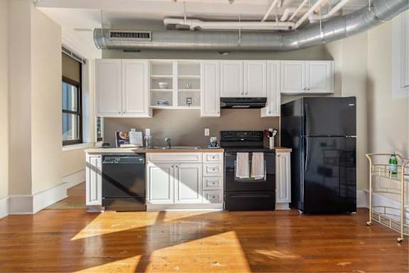 A kitchen with black appliances and white cabinets.