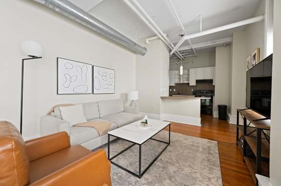 A living room with a white couch and a brown leather chair.