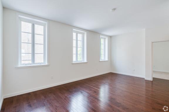 A room with wooden floors and three windows.