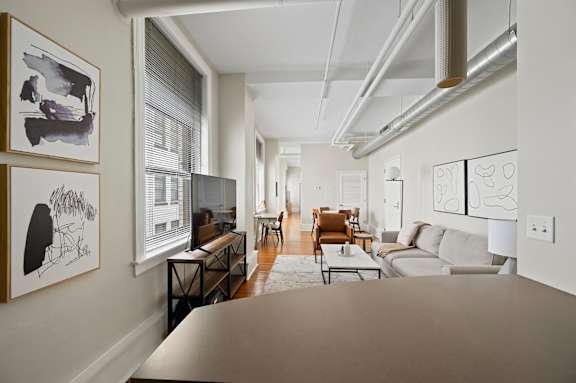 A living room with a couch, chairs, and pictures on the wall.
