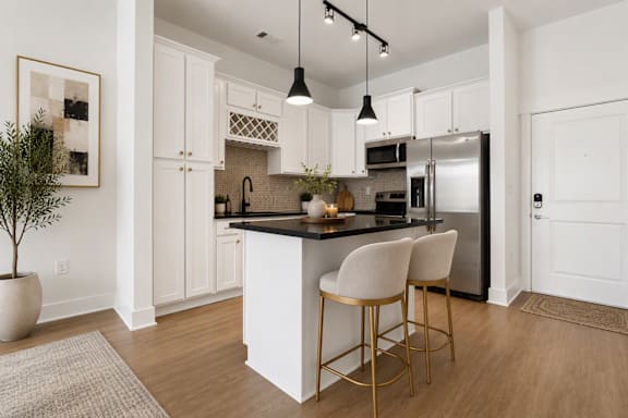 A kitchen with white cabinets and a black countertop.