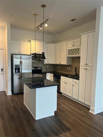 A kitchen with white cabinets and a black countertop.