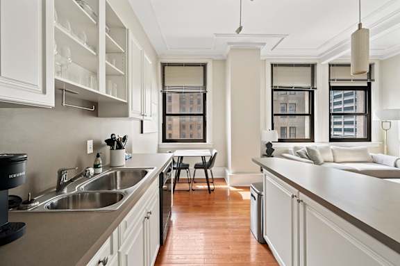 A kitchen with white cabinets and a wooden floor.