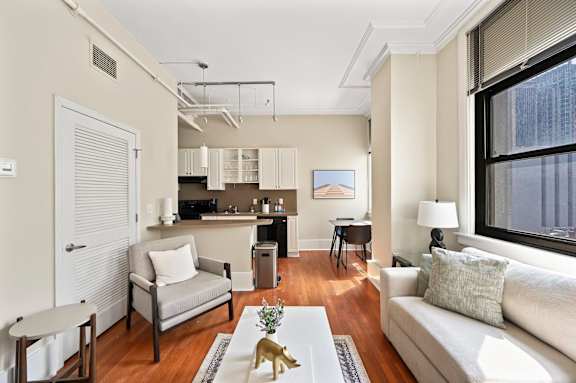 A living room with a grey couch and a coffee table with a gold vase on it.