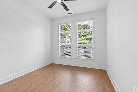 A room with a ceiling fan and a window with blinds.