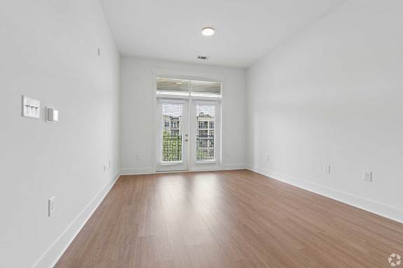 A room with wooden floors and a window with blinds.